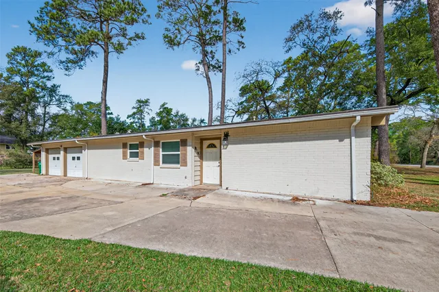 front view of house with potted plants and large trees
