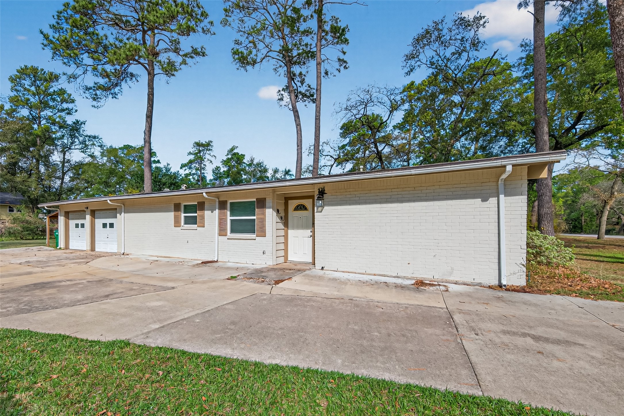 front view of house with potted plants and large trees
