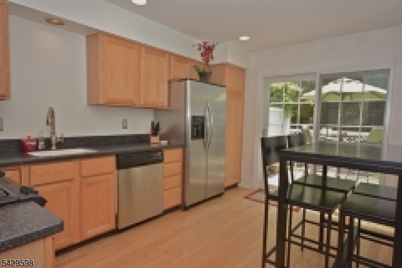 105 Well Sweep Road, Unit 105 Whitehouse Station, NJ 08889 - Photo 4 of 22 a kitchen with stainless steel appliances granite countertop a table chairs sink and cabinets