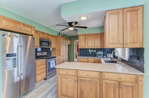 a kitchen with stainless steel appliances granite countertop a refrigerator a sink dishwasher a stove with wooden cabinets and floor