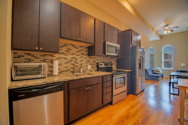 a kitchen with stainless steel appliances granite countertop a stove a sink dishwasher and a microwave oven with cabinets