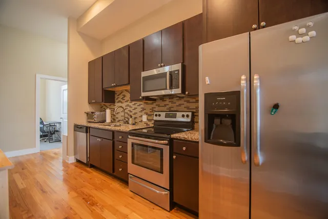 a kitchen with stainless steel appliances kitchen island granite countertop a stove a sink and a refrigerator