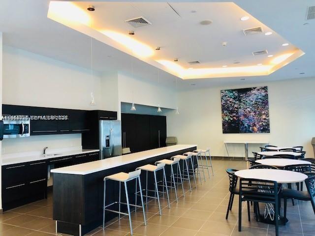 79 Southwest 12th Street, Unit 2402S Miami, FL 33130 - Photo 18 of 23 a dinning room with stainless steel appliances kitchen island granite countertop a table chairs and a refrigerator