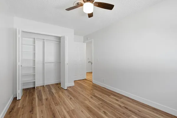 a view of empty room with wooden floor and fan