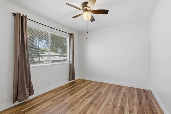 a view of a hallway with wooden floor and a bathroom