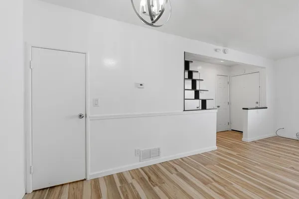 a view of a livingroom with wooden floor and kitchen space