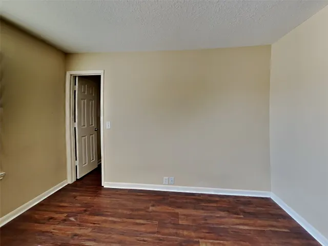 a view of an empty room with wooden floor and closet
