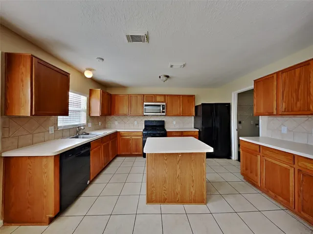 a kitchen with stainless steel appliances a sink counter top space cabinets and a window