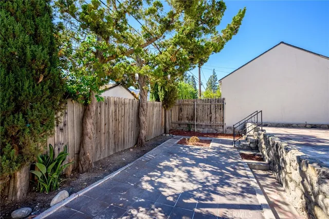 a view of a backyard with wooden fence and a large tree