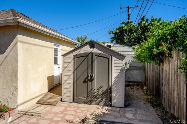 a view of a wooden house with a small yard and wooden fence