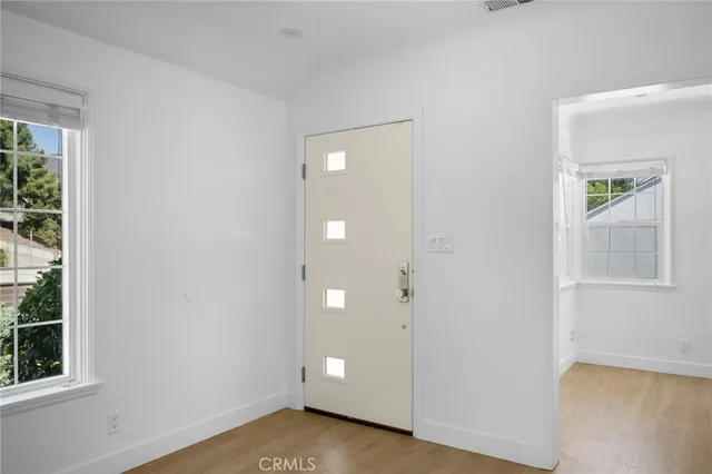 a view of an empty room with window and wooden floor