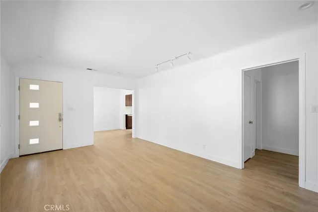a view of an empty room with wooden floor and closet