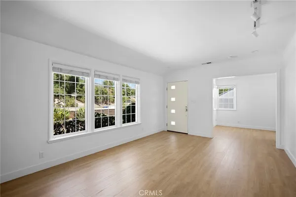 a view of an empty room with wooden floor and windows