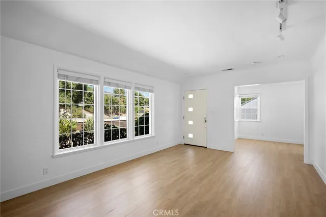 a view of an empty room with wooden floor and windows