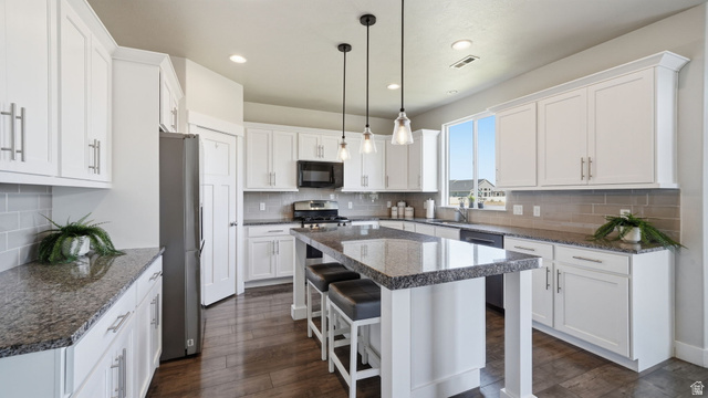 111 East Silver Oak Road Vineyard, UT 84059 - Photo 11 of 50 Kitchen featuring a large island with seating, white shaker cabinetry, stone-finish countertops, stainless steel appliances, and wood-finish flooring