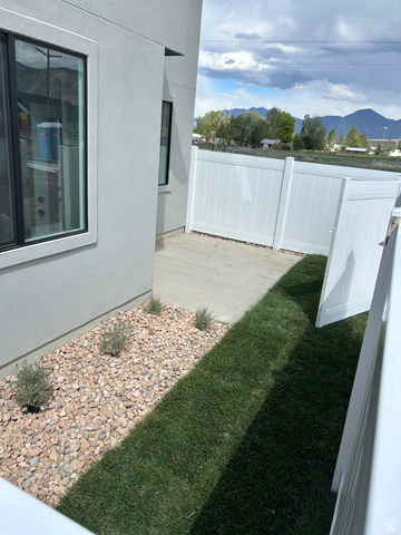2011 West 1150 South, Unit 1042 Payson, UT 84651 - Photo 4 of 39 Photos are of model home.Paved patio area featuring a white privacy fence, an adjacent gravel bed with plantings, and a strip of manicured lawn