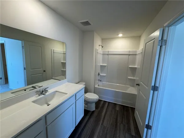 a bathroom with a sink a toilet a mirror and shower