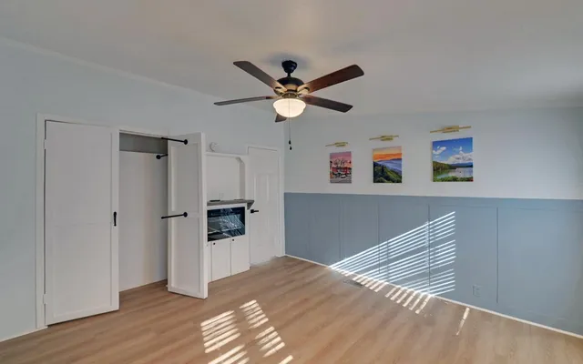 a view of a livingroom with a ceiling fan wooden floor and a ceiling fan