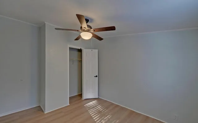 an empty room with wooden floor and a ceiling fan