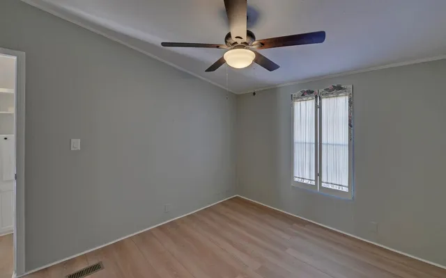 an empty room with a window and ceiling fan