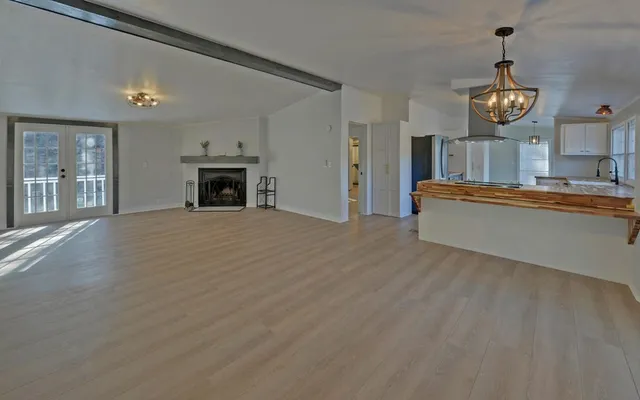 a view of a livingroom with furniture a fireplace a chandelier and wooden floor