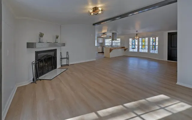 a view of an empty room with wooden floor and a fireplace