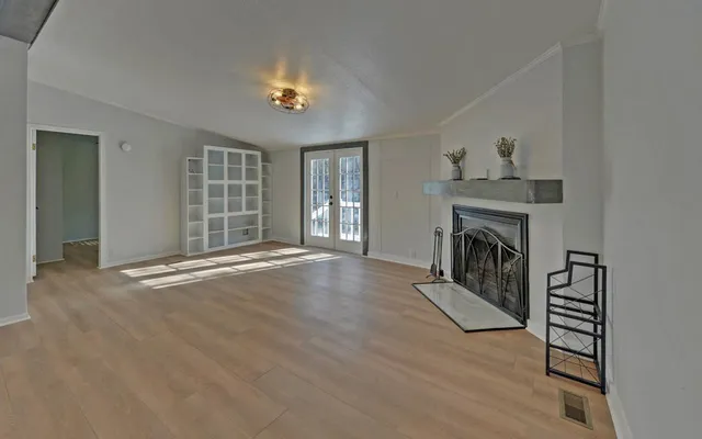 an empty room with fireplace chandelier and windows