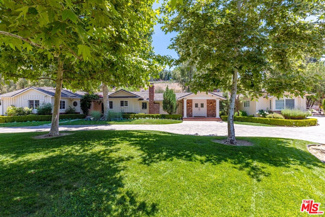 a front view of a house with a yard and green space