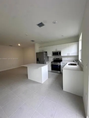 a kitchen with stainless steel appliances kitchen island granite countertop a refrigerator stove and sink