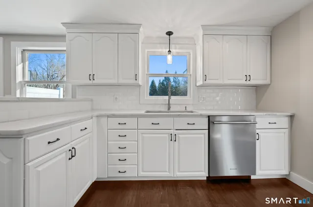 a kitchen with stainless steel appliances granite countertop white cabinets and window
