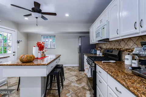 a kitchen with stainless steel appliances granite countertop a sink a stove and a wooden cabinets