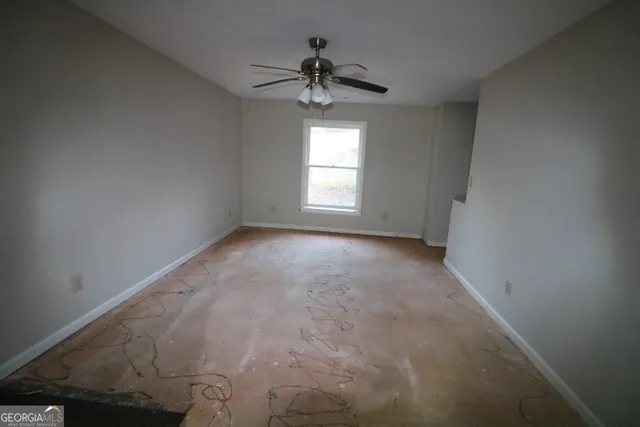 en empty room with windows and ceiling fan