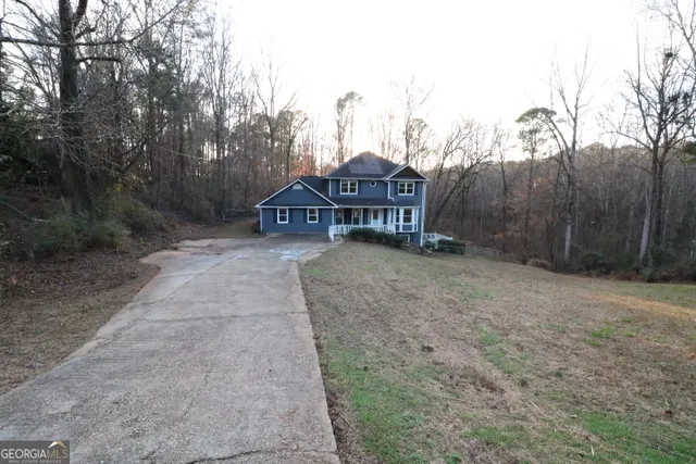 a view of a house with large trees and wooden fence