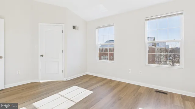 an empty room with wooden floor and windows