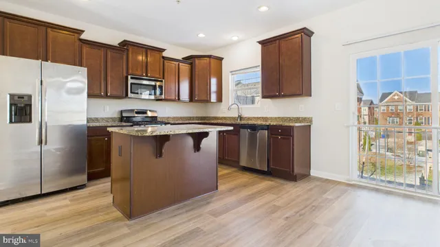 a kitchen with stainless steel appliances granite countertop a stove a sink dishwasher a refrigerator and a microwave oven with wooden floor