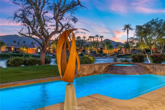 a view of a swimming pool with a yard and palm trees