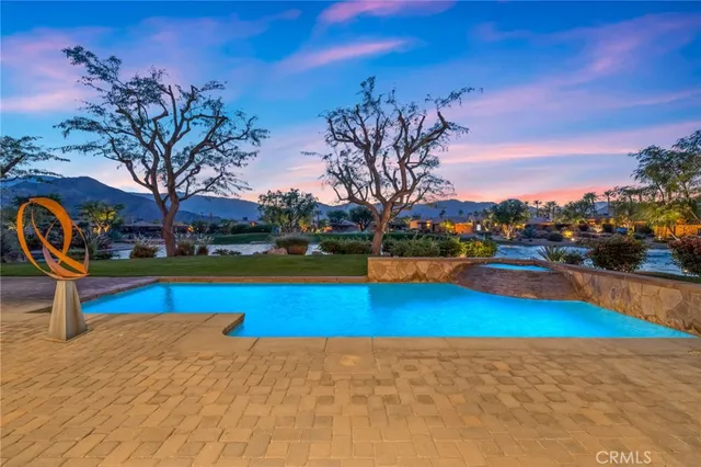 a view of swimming pool with outdoor seating and trees in the background