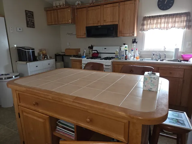 a kitchen with stainless steel appliances kitchen island granite countertop a sink a stove and a microwave