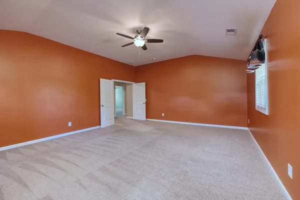 a view of an empty room with windows and ceiling fan