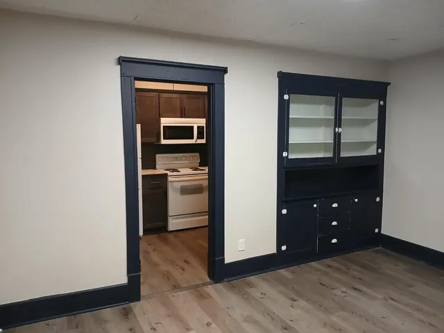 a view of empty room with kitchen and wooden floor