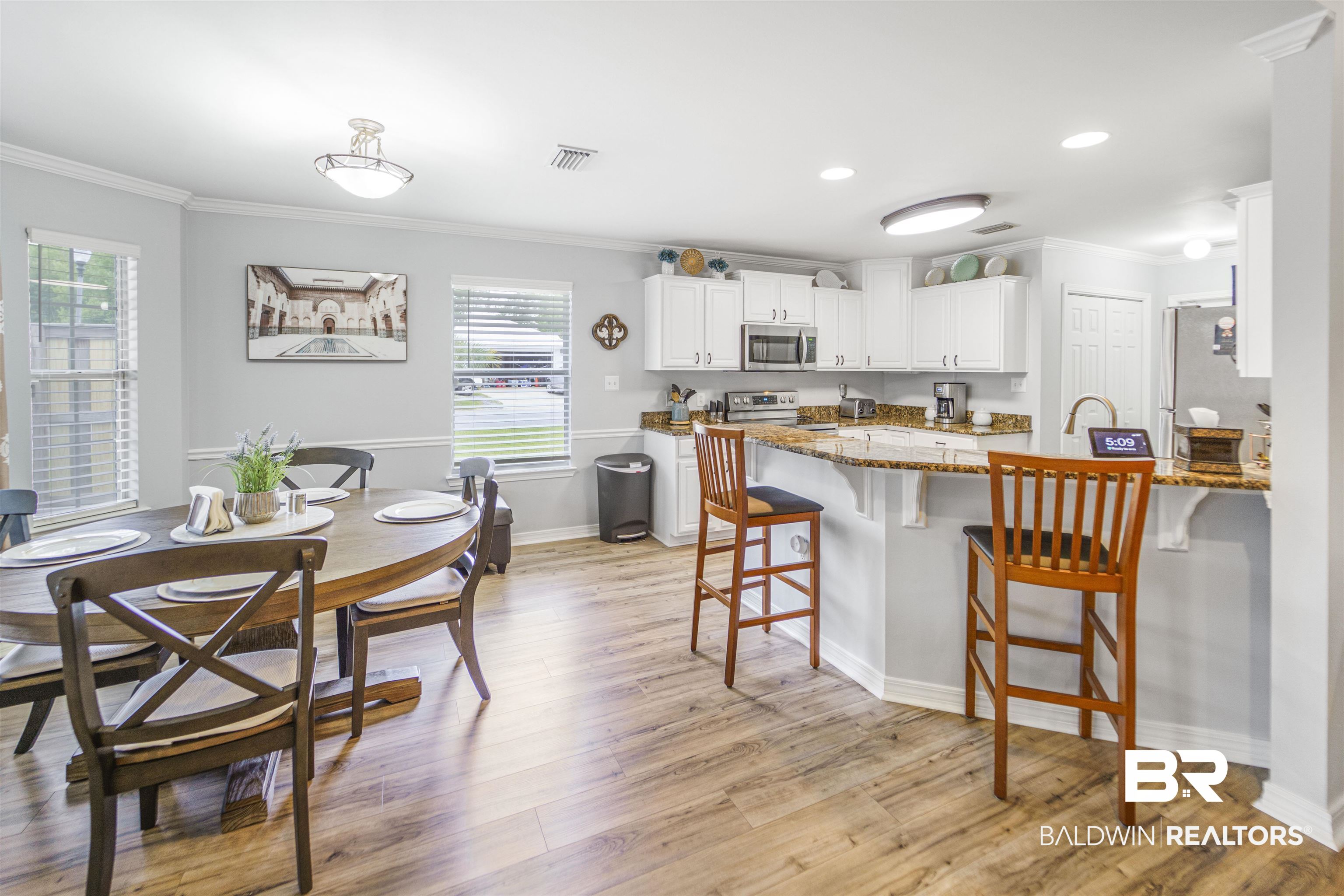 4620 Pine Boulevard Orange Beach, AL 36561 - Photo 9 of 49 Kitchen with stainless steel microwave, crown molding, a peninsula, healthy amount of natural light, and a breakfast bar area