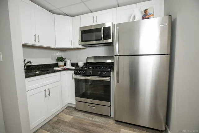 a kitchen with cabinets stainless steel appliances and wooden floor