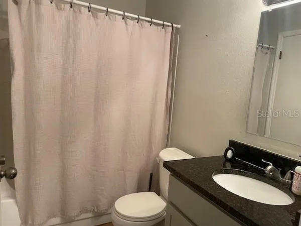 a bathroom with a granite countertop sink toilet and a mirror