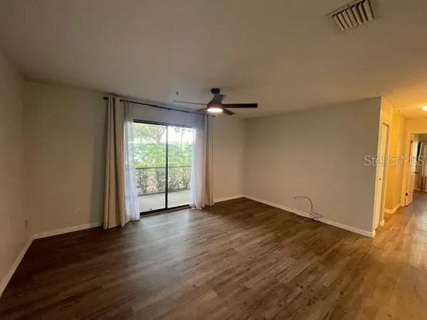 a view of an empty room with wooden floor and a window