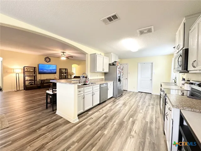 a kitchen with table chairs microwave and cabinets