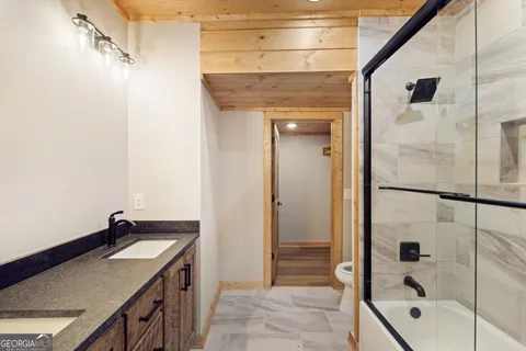a bathroom with a granite countertop sink a mirror and shower