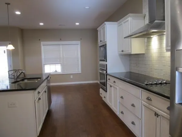 a kitchen with granite countertop a sink stove and cabinets