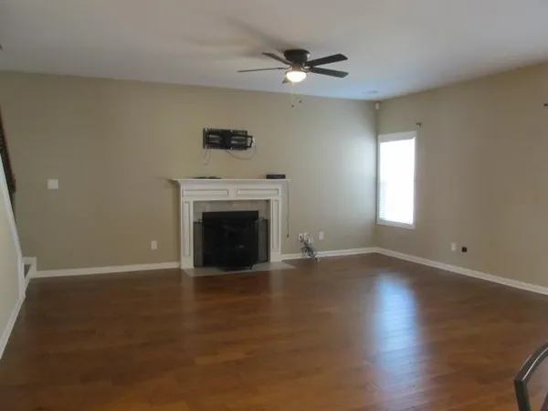 an empty room with wooden floor a fireplace and windows