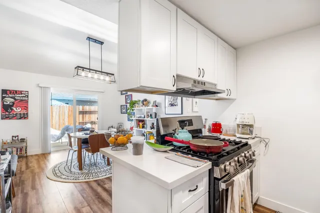 a kitchen with a sink dishwasher a dining table and chairs with wooden floor