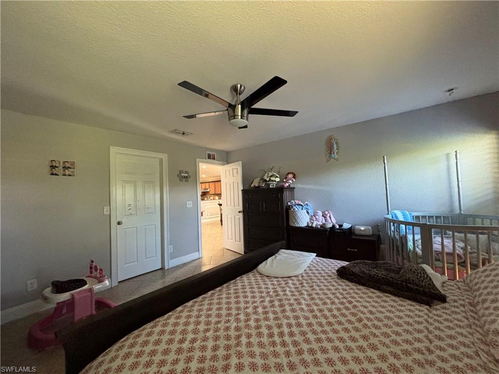 1243 Madison Court Immokalee, FL 34142 - Photo 13 of 32 a bedroom with a bed a dresser and potted plant